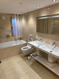 a bathroom with a sink and a tub and a toilet at Hotel du Lac in Villars-sur-Ollon