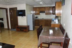 a kitchen with a table and a refrigerator at الأحفاد للشقق الفندقية Al Ahfad Hotel Apartments in Şāfūţ