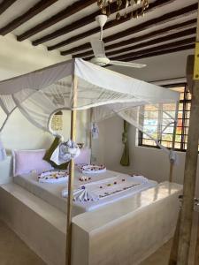 Villa Upendo Paje في باجي: سرير أبيض مع ستارة في الغرفة