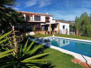 a villa with a swimming pool in front of a house at Paraje El Pozo in Málaga