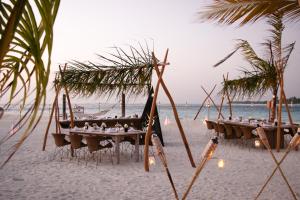 a beach with tables and chairs on the beach at Nazaki Beach Hotel & Spa Maldives in Gan
