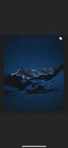 Hotel du Lac في فيلار سور أولون: اطلالة على جبل مغطى بالثلج ليلا