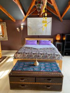 um quarto com uma cama com almofadas roxas e um tecto de madeira em Tienne Del Mar em Paul