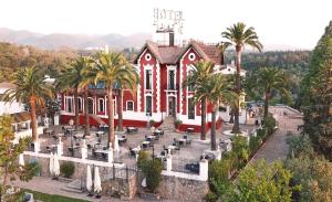 een groot rood gebouw met palmbomen ervoor bij Hotel Finca Los Abetos in Córdoba