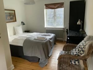 a bedroom with a bed and a chair and a window at Hotel Saxkjøbing in Sakskøbing