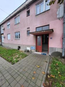 un edificio rosa con una puerta roja y una acera en Felix apartman Zajecar, en Zajecar