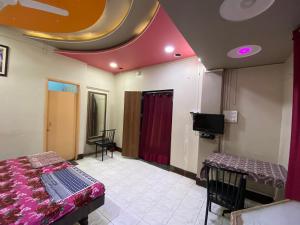 Habitación con cama y TV. en MUKTAI LODGE en Solāpur