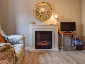 a living room with a fireplace and a tv at Jasmine Cottage in Chipping Campden