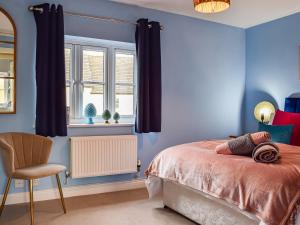 a bedroom with blue walls and a bed and a chair at Jasmine Cottage in Chipping Campden