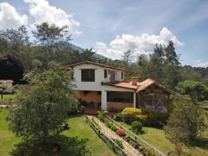 a small white house with a garden in front of it at Monte Verde Cabañas y Camping in Arcabuco