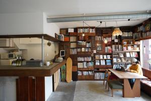 a room with a library with a person sitting at a table at 白馬シェア Hakuba share in Hakuba