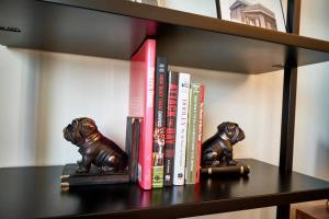 un estante de libros con libros y dos estatuas de perros en UGA Penthouse Downtown Athens Walk To Stadium, en Athens