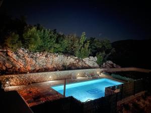 ein Schwimmbad in der Nacht mit Lichtern auf den Felsen in der Unterkunft Villa Marina in Zagvozd