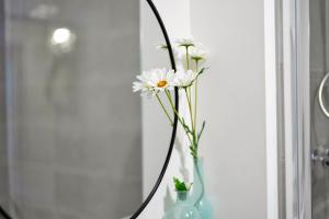 een vaas met witte bloemen voor een spiegel bij Fortified Two Bedroom Home - Bristol in Whitchurch
