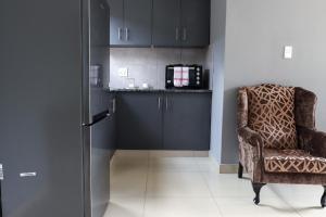 a room with a chair and a kitchen with black cabinets at 235 LODGE in Durban