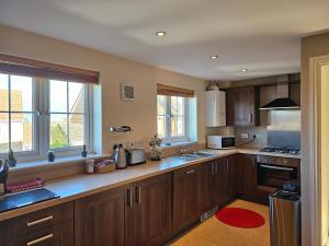 a large kitchen with wooden cabinets and windows at Holly Crescent, Sacriston DH7 in Sacriston