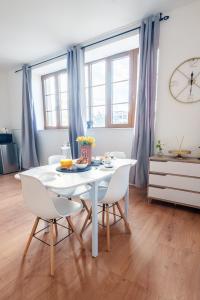 a white table and chairs in a room with a clock at Le Fleur de Cerisier - ZMN Conciergerie in Saint-Quentin