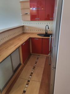 una piccola cucina con armadi rossi e lavandino di 2 pokojowy apartament a Stettino
