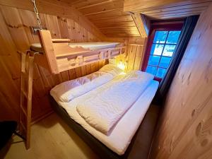 Cama pequeña en habitación de madera con ventana en Flott hytte i Vrådal rett ved alpinbakken en Vradal
