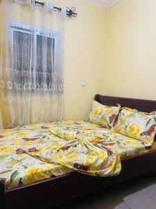 a bedroom with a bed with a yellow and white comforter at LNIMMO-LAGRACE-Studio calme avec internet illimité et forage in Yaoundé