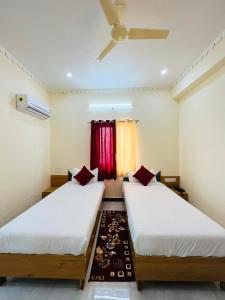 two beds in a room with a ceiling fan at Jai hari vilas in Jodhpur