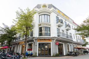 ein weißes Gebäude mit Motorrädern, die davor geparkt sind in der Unterkunft Nét Việt Hotel Vincom Sóc Trăng in Soc Trang