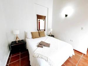 a white bedroom with a white bed with two lamps at 65 Fortaleza 1 - N Colonial Apt W/ Balconies & Views in San Juan