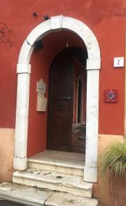 une arche menant à un bâtiment rouge avec une porte dans l'établissement B&B Villa la Canonica a Padernello, 