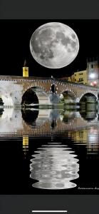 Un homme traversant un pont avec une lune dans le ciel dans l'établissement Residenza Bra Verona, à Vérone