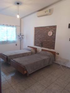 two beds in a room with a clock on the wall at DEPARTAMENTO LA TINAJA in Villa Krause