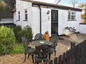 a patio with a table and chairs and a house at Stores Cottages in Ludham