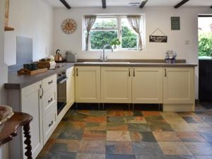 a kitchen with white cabinets and a tile floor at Stores Cottages in Ludham