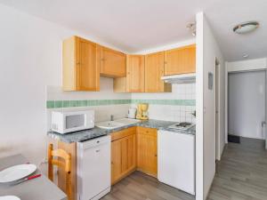 a kitchen with wooden cabinets and a white microwave at Appartement La Mongie, 2 pièces, 5 personnes - FR-1-404-57 in La Mongie
