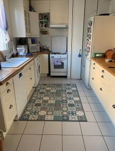 a kitchen with white cabinets and a tile floor at Paris & Versailles at your feet! Shared room in nice house in Meudon