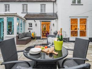 a patio with a table and chairs with a bottle of wine at Victoria Cottage in Christchurch