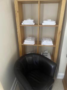 un fauteuil en cuir noir devant une étagère avec des serviettes dans l'établissement Leamington Loft, à Leamington Spa