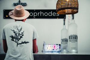 a man in a hat standing at a counter with two bottles at Hotel Parthenon Rodos city in Rhodes Town