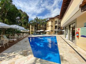 una grande piscina accanto a un edificio di FLAT COM VARANDA E SERVIÇOS NO RIVIERA GREEN a Bertioga