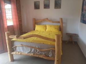 ein Schlafzimmer mit einem Holzbett mit gelber Bettwäsche in der Unterkunft Casa dos Sonhos Hospedaria in Sêrro