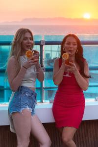 two women sitting on a balcony holding wine glasses at Hotel Parthenon Rodos city in Rhodes Town
