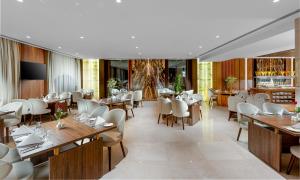 فندق جايدن-Jayden Hotel في المدينة المنورة: مطعم بطاولات خشبية وكراسي بيضاء