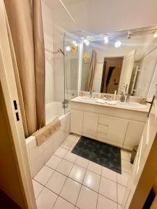 een badkamer met een bad, een wastafel en een spiegel bij Paris & Versailles at your feet! Shared room in nice house in Meudon