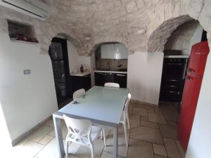 a kitchen with a table and chairs in a room with stone walls at Trullo Civico 25, Cummersa Civico 23 in Alberobello