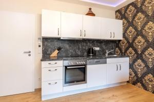 cocina con armarios blancos y fogones en PMC Business Apartments en Rüsselsheim