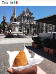 una mano sosteniendo un pedazo de pan delante de un edificio en HAPPY HISTORIC HOUSE, en Catania
