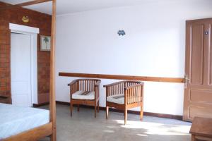 アンタナナリボにあるHotel Mahaveloのベッドルーム1室(椅子2脚、ベッド1台、鏡付)