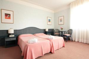 una camera da letto con un grande letto con lenzuola rosa di Hotel Abbazia a Grado