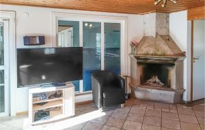 uma sala de estar com televisão e lareira em Beautiful Home In Kpingsvik With Sauna, Wifi And Indoor Swimming Pool em Grönskog