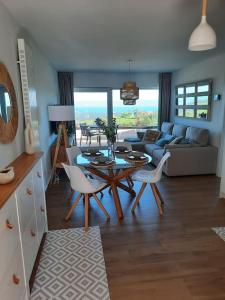 sala de estar con mesa, sillas y sofá en Vistas al mar y con jardín - Casa Abelia, en Canales