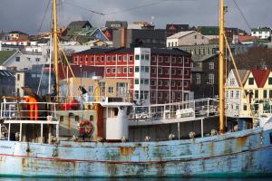 an old boat sitting in the water next to a city at Hotel Tórshavn in Tórshavn